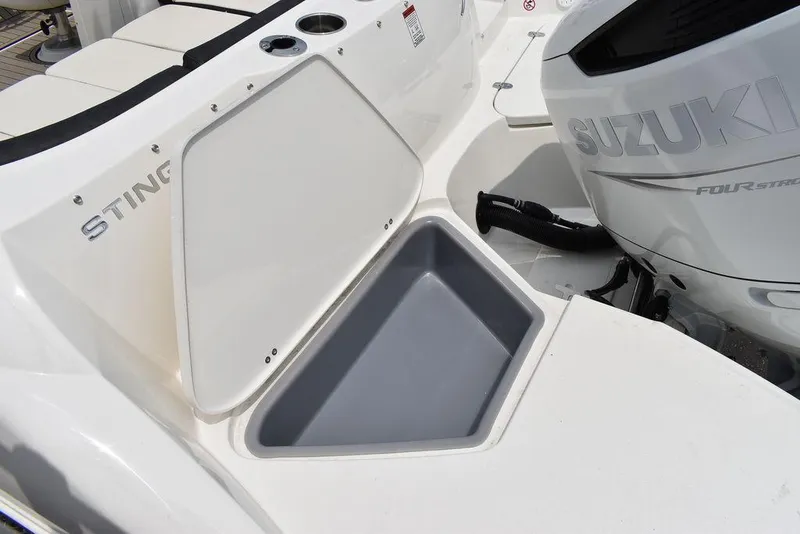 Slide: The Image of 2023 Stingray 231DC boat with open storage compartment and Suzuki outboard motor. - 13