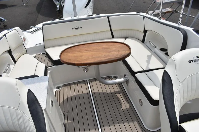Slide: The Image of 2023 Stingray 231DC boat interior with cushioned seating and wooden table. - 44