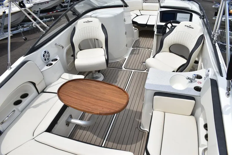 Slide: The Image of 2023 Stingray 231DC boat interior with white seating and wooden table. - 45