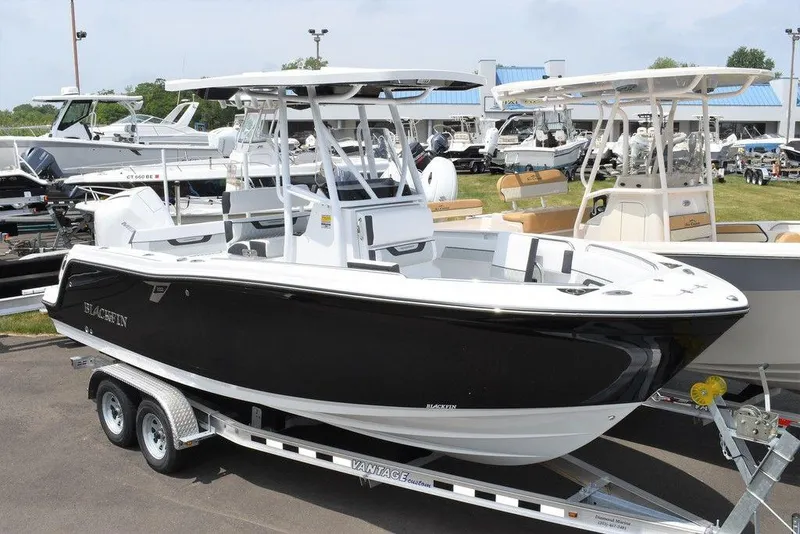 The Image of 2024 Blackfin 222CC boat on trailer, sleek black and white design, outdoor display. - 1