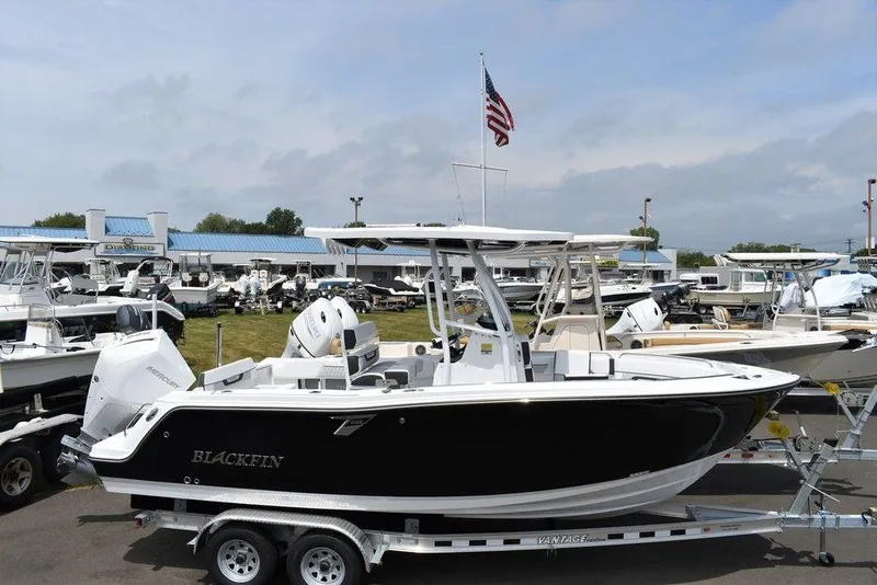 Slide: The Image of 2024 Blackfin 222CC boat on trailer, displayed at a marina with American flag. - 3