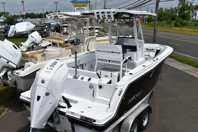 Slide: The Image of 2024 Blackfin 222CC boat on trailer, parked near road, showcasing sleek design and powerful engine. - 6