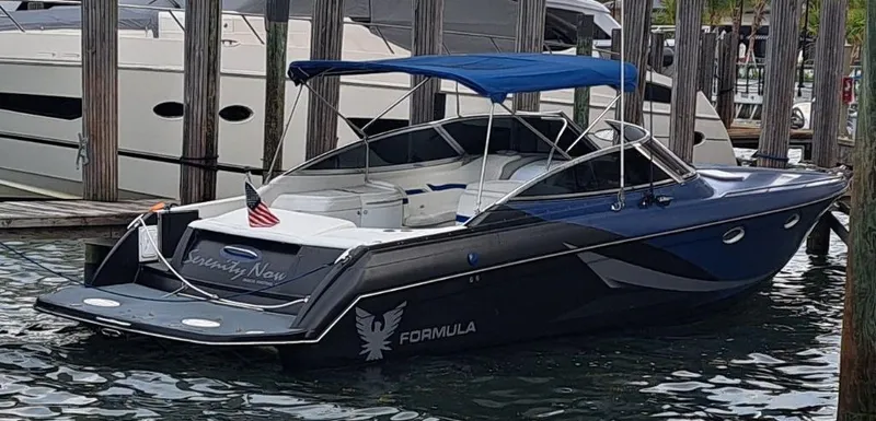 Slide: The Image of 2002 Formula 330 SS boat docked with blue canopy and American flag. - 4