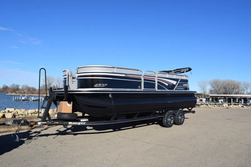 Slide: The Image of 2023 Ranger 223C pontoon boat on a trailer by the waterfront. - 1