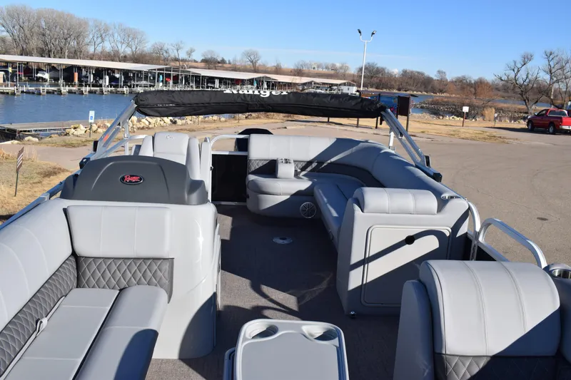 Slide: The Image of 2023 Ranger 223C pontoon boat with spacious seating and modern design at a lakeside dock. - 15