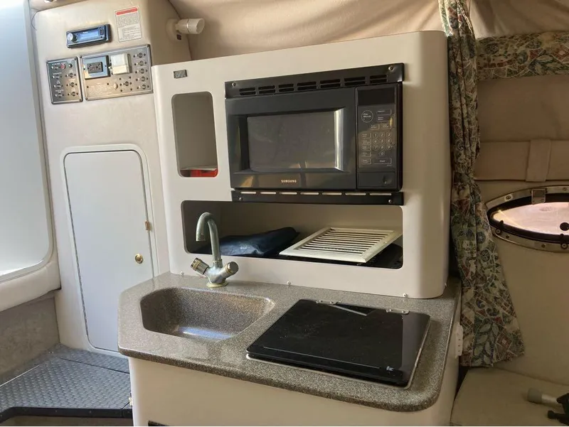 Slide: The Image of Compact kitchen area in a 2000 Crownline 268 boat with microwave, sink, and control panel. - 5