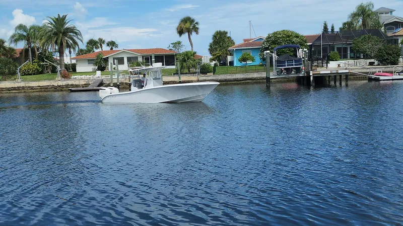 Slide: The Image of 2005 Yellowfin 31 boat cruising on a scenic waterfront with palm trees and houses. - 23