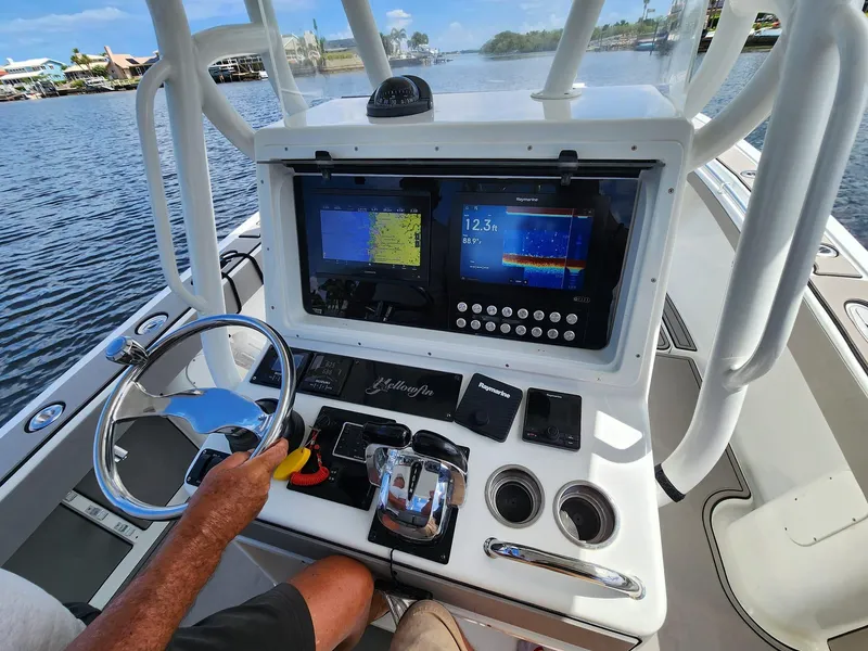 Slide: The Image of 2005 Yellowfin 31 boat dashboard with navigation screens and steering wheel on water. - 6
