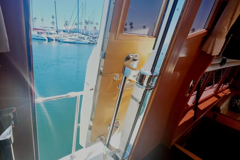 Slide: The Image of 1999 McKinna 57 Pilothouse yacht interior with open door, overlooking marina and sailboats. - 18
