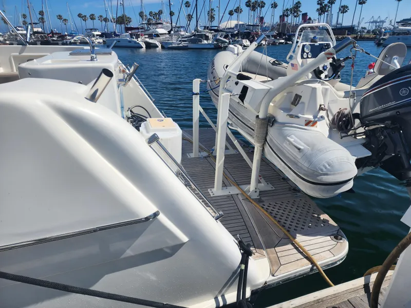 Slide: The Image of 1999 McKinna 57 Pilothouse yacht with dinghy at marina, surrounded by boats and palm trees. - 25