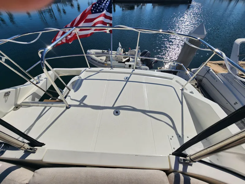 Slide: The Image of 1999 McKinna 57 Pilothouse yacht deck with American flag, overlooking marina waters. - 28