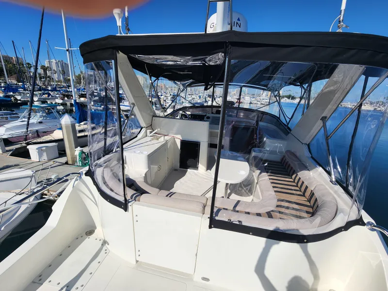 Slide: The Image of 1999 McKinna 57 Pilothouse yacht with spacious seating, docked at a marina under clear blue skies. - 29