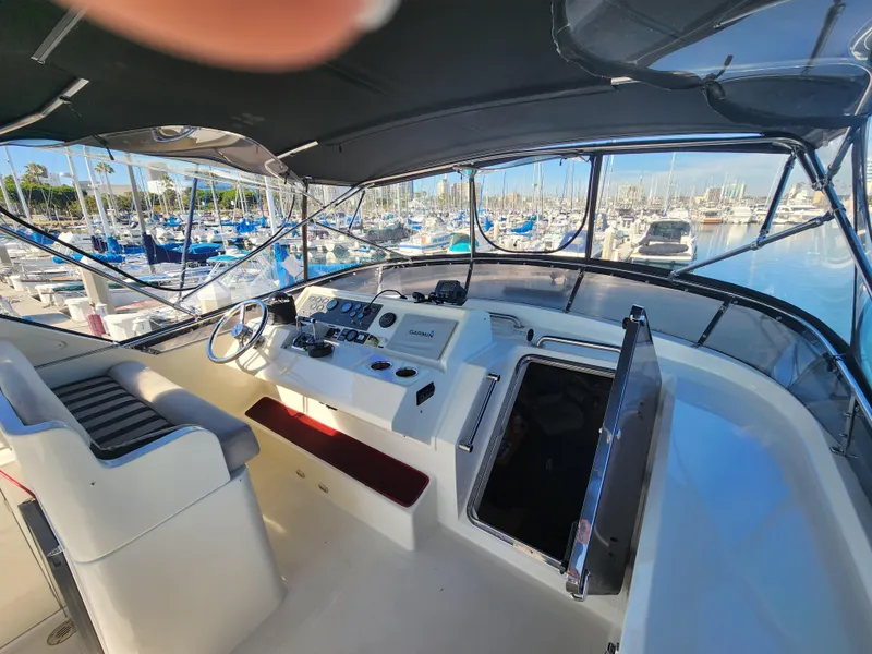 Slide: The Image of 1999 McKinna 57 Pilothouse yacht helm with marina view, featuring modern controls and seating. - 32
