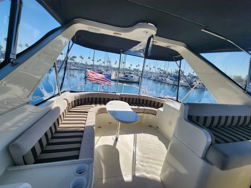 Slide: The Image of 1999 McKinna 57 Pilothouse yacht interior with striped seating and marina view. - 33