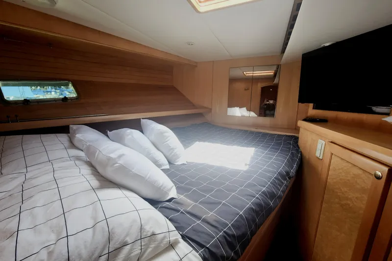 Slide: The Image of 1999 McKinna 57 Pilothouse bedroom with cozy bedding, wooden interior, and a wall-mounted TV. - 9