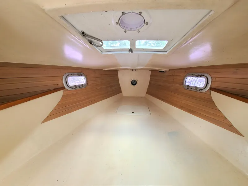 Slide: The Image of Interior cabin of 2016 Farrier F-25C #22 sailboat with wooden accents and portholes. - 6