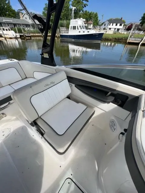 Slide: The Image of 2013 Sea Ray 240 Sundeck boat interior with white seating, docked by waterfront homes. - 13