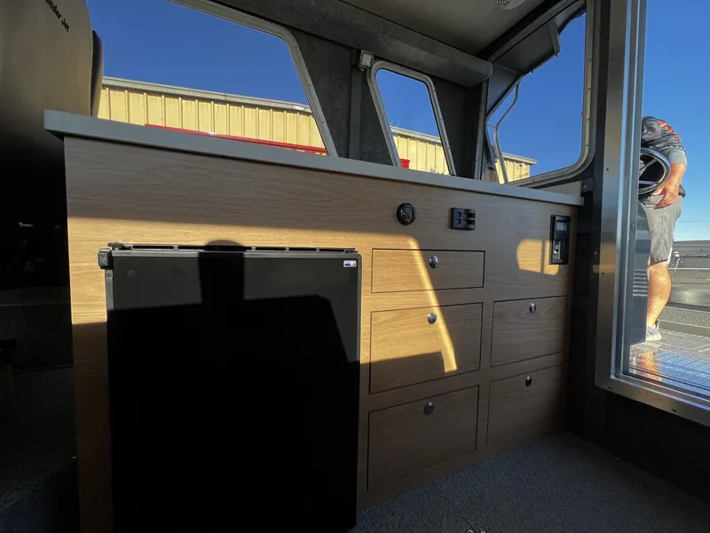 Slide: The Image of Interior of 2023 Thunder Jet 26 Pilot boat with wooden cabinetry and mini-fridge. - 12