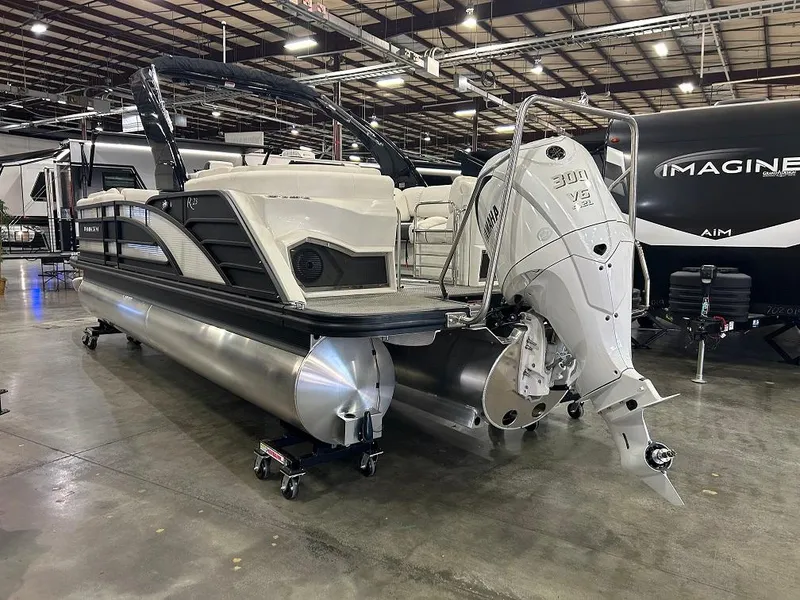 Slide: The Image of 2024 Bennington 23 RFBA pontoon boat with powerful outboard motor in a showroom. - 2