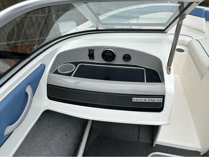 Slide: The Image of 2013 Bayliner 185 boat interior dashboard with storage compartment and cup holder. - 9