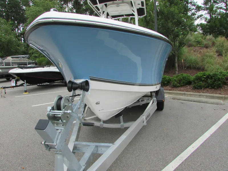 Slide: The Image of 2023 Mako 214 CC boat on trailer, blue hull, parked outdoors. - 11