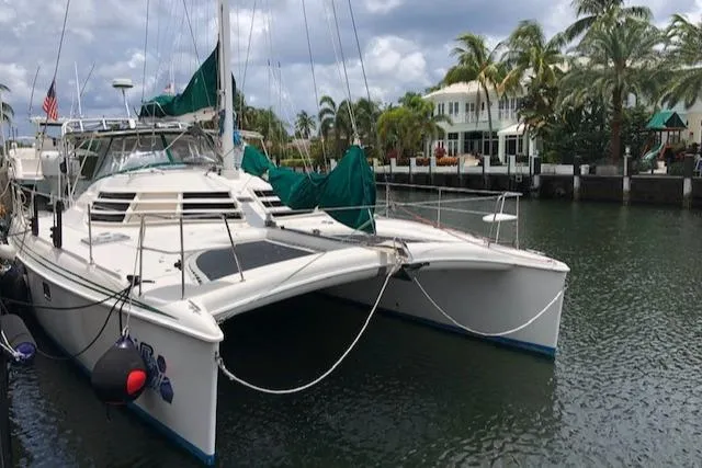 The Image of 2005 Manta 42 MK II catamaran docked by palm trees and waterfront homes. - 0