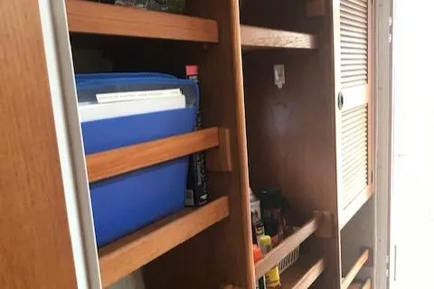 Slide: The Image of Wooden storage shelves inside a 2005 Manta 42 MK II boat, holding various items. - 15