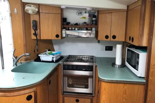Slide: The Image of Compact kitchen in a 2005 Manta 42 MK II yacht with stove, microwave, and wooden cabinetry. - 7