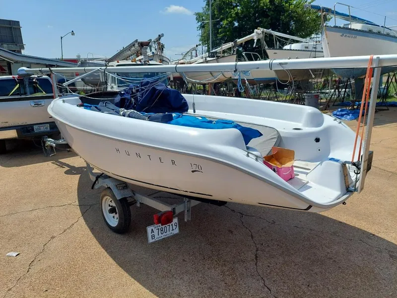 Slide: The Image of 1998 Hunter 170 sailboat on trailer, parked outdoors with other boats in the background. - 5