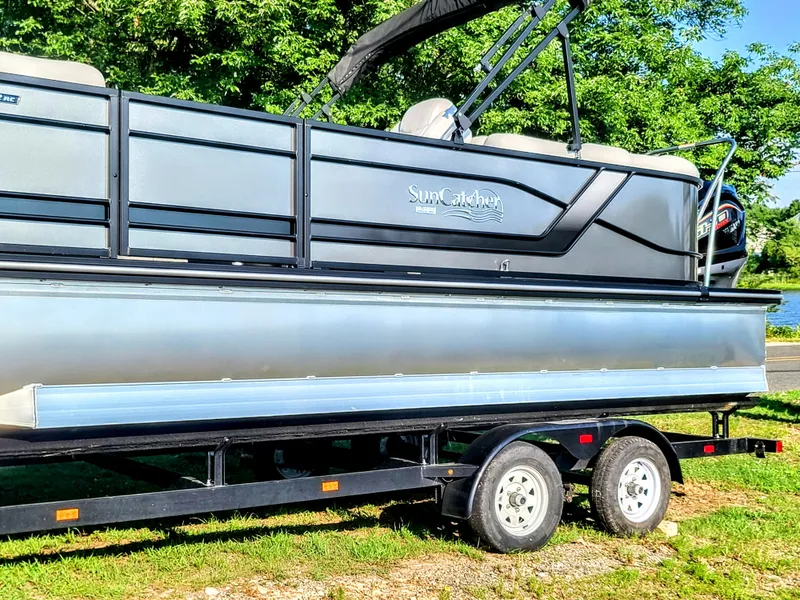 Slide: The Image of 2023 SunCatcher Fusion 322RC pontoon boat on a trailer, side view. - 2