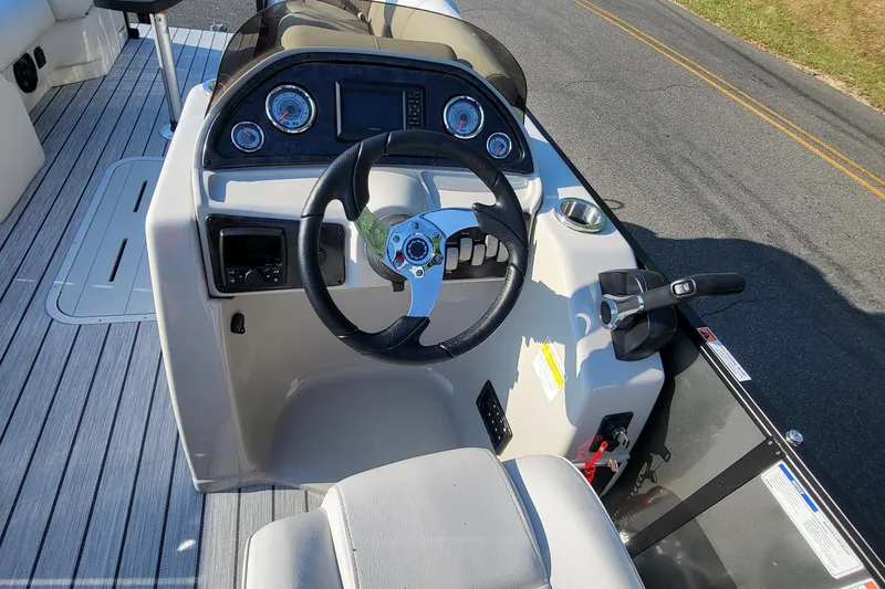 Slide: The Image of 2023 SunCatcher Fusion 322RC boat dashboard with steering wheel and control panel. - 9