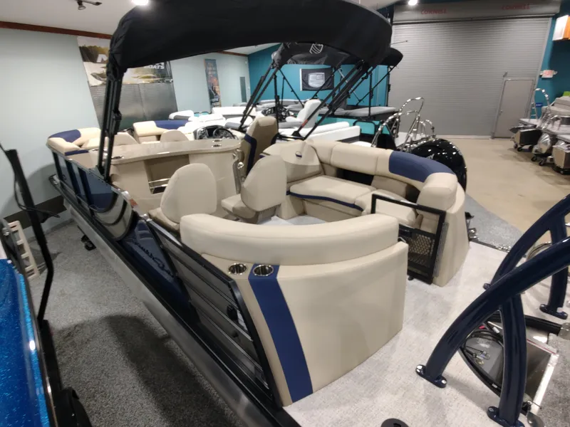 Slide: The Image of 2024 South Bay 523E 2.75 pontoon boat with beige and blue seating in showroom. - 10