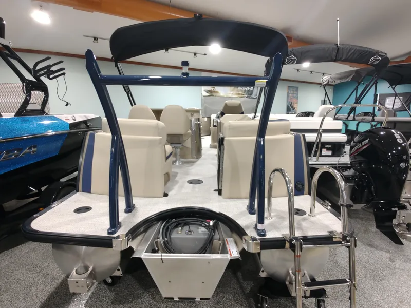 Slide: The Image of 2024 South Bay 523E 2.75 pontoon boat in showroom, rear view with ladder and seating. - 3
