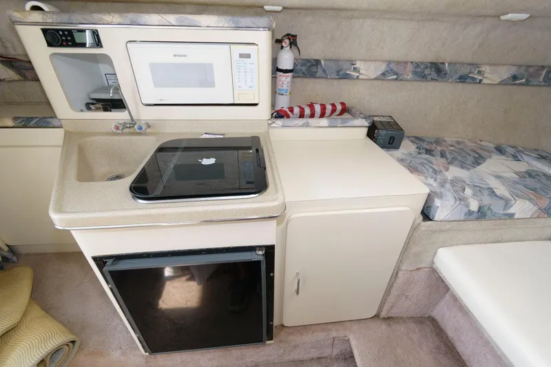 Slide: The Image of 1998 Wellcraft 260 SE boat interior with kitchenette, microwave, sink, and mini-fridge. - 11
