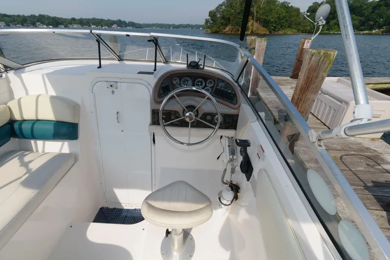 Slide: The Image of 1998 Wellcraft 260 SE boat cockpit with steering wheel and controls, docked by the water. - 3