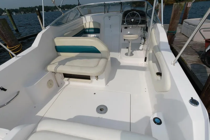 Slide: The Image of 1998 Wellcraft 260 SE boat interior with white and teal seating, docked by the water. - 5