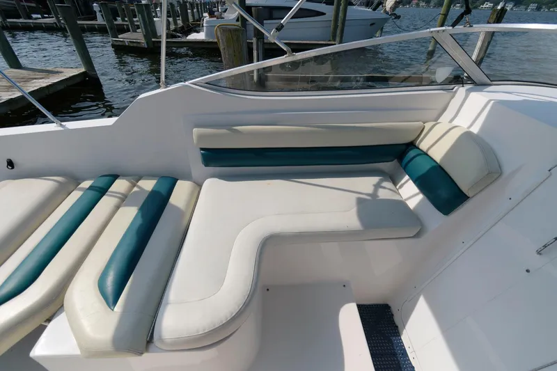 Slide: The Image of 1998 Wellcraft 260 SE boat interior with white and teal seating at a marina. - 7