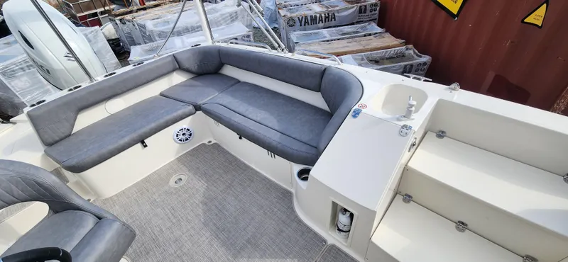 Slide: The Image of 2022 Stingray 212SC boat interior with gray seating, sink, and storage compartments. - 6