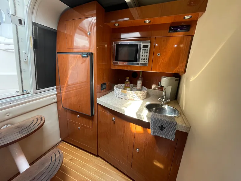 Slide: The Image of 2005 Regal Commodore 3560 IB yacht kitchen with wood cabinetry, microwave, sink, and refrigerator. - 27