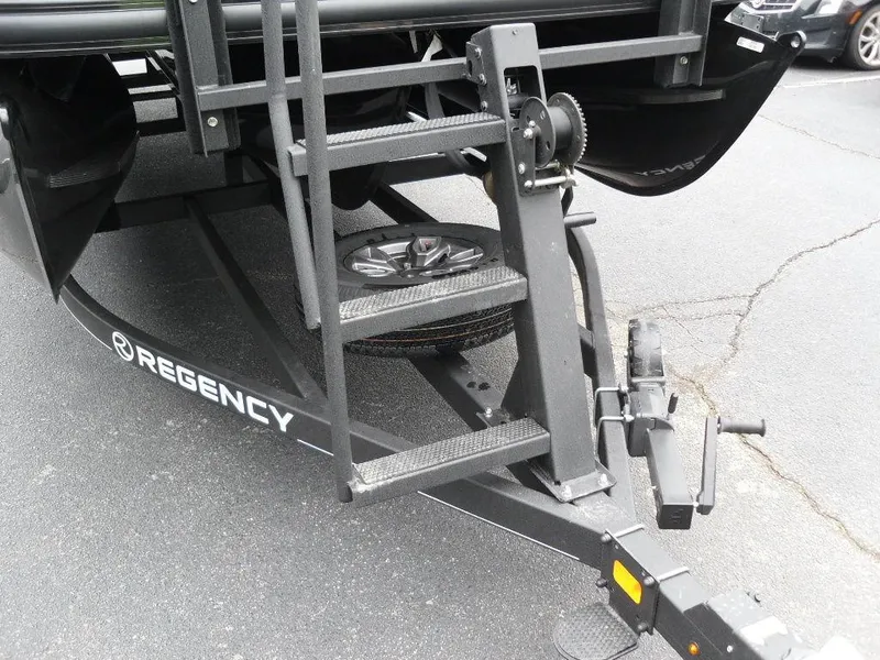 Slide: The Image of 2024 Regency 250 DL3 boat trailer with steps and winch on asphalt surface. - 10