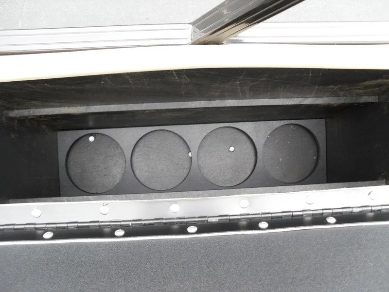 Slide: The Image of 2024 Regency 250 DL3 storage compartment with circular holders, open lid view. - 23