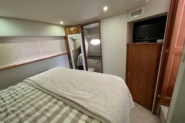 Slide: The Image of 2000 Silverton 392 Motor Yacht bedroom with bed, TV, and ensuite bathroom. - 55