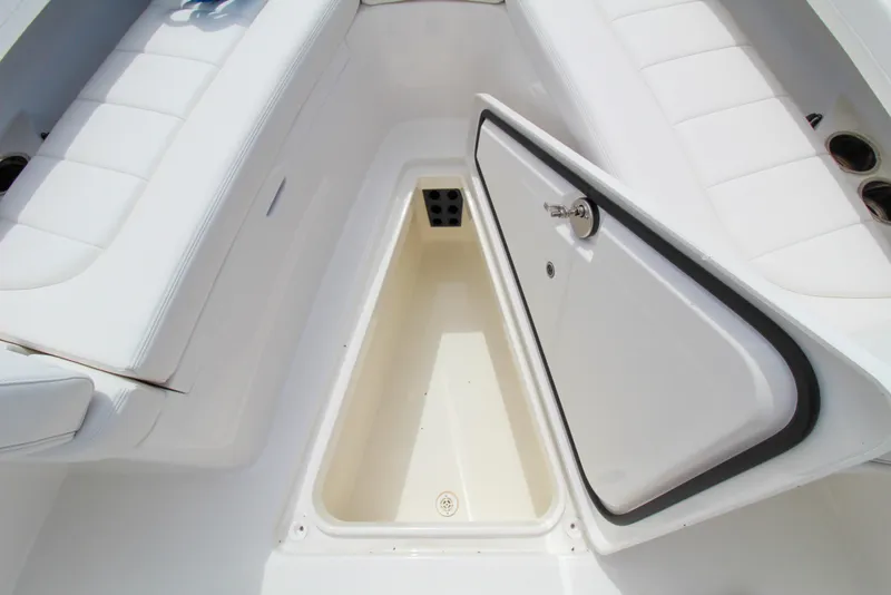 Slide: The Image of 2024 Regulator 23 boat storage compartment with open hatch and white seating. - 16