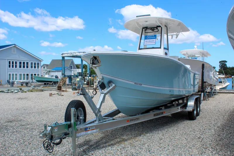 Slide: The Image of 2024 Regulator 23 boat on trailer at marina, clear sky background. - 2