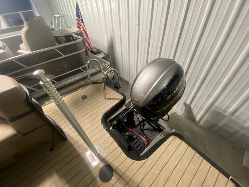 Slide: The Image of 2024 Starcraft EXS 1 pontoon boat with outboard motor and American flag. - 4
