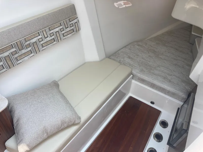 Slide: The Image of 2023 Pursuit DC 365 cabin interior with cushioned seating and decorative pillow. - 11