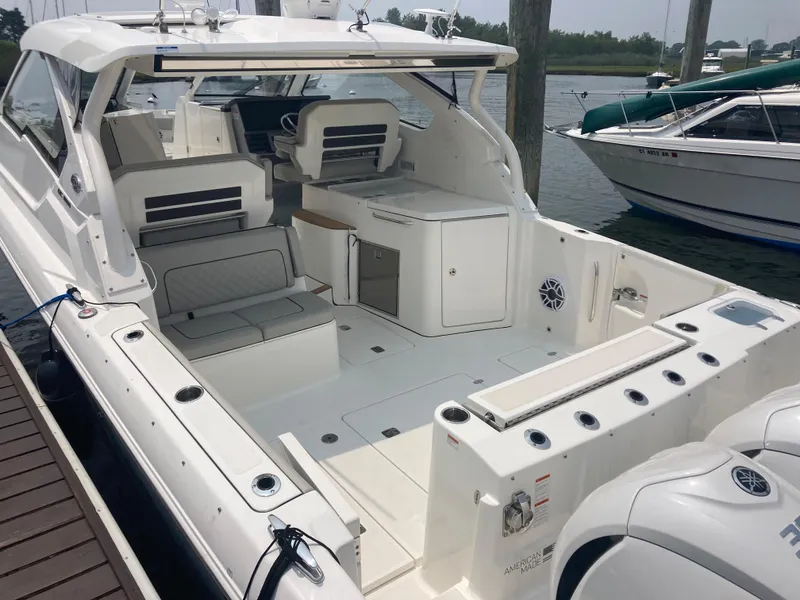 Slide: The Image of 2023 Pursuit DC 365 boat interior with seating and storage at a marina. - 4