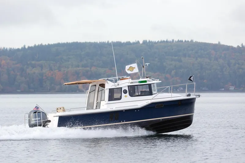 The Image of 2024 Ranger Tugs R-25 cruising on a lake with forested hills in the background. - 1