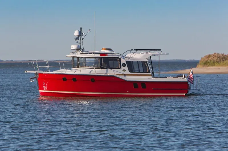 The Image of 2024 Ranger Tugs R-29 boat cruising on calm water near a sandy shore. - 1