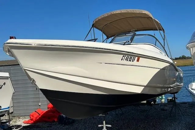 The Image of 2023 Scout 210 Dorado boat with canopy, docked on gravel near water. - 0